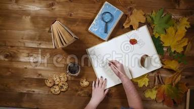 秋季概念俯视图.. 书，枫叶，旧木桌上的茶.. 女人在<strong>笔记</strong>本上写<strong>笔记</strong>